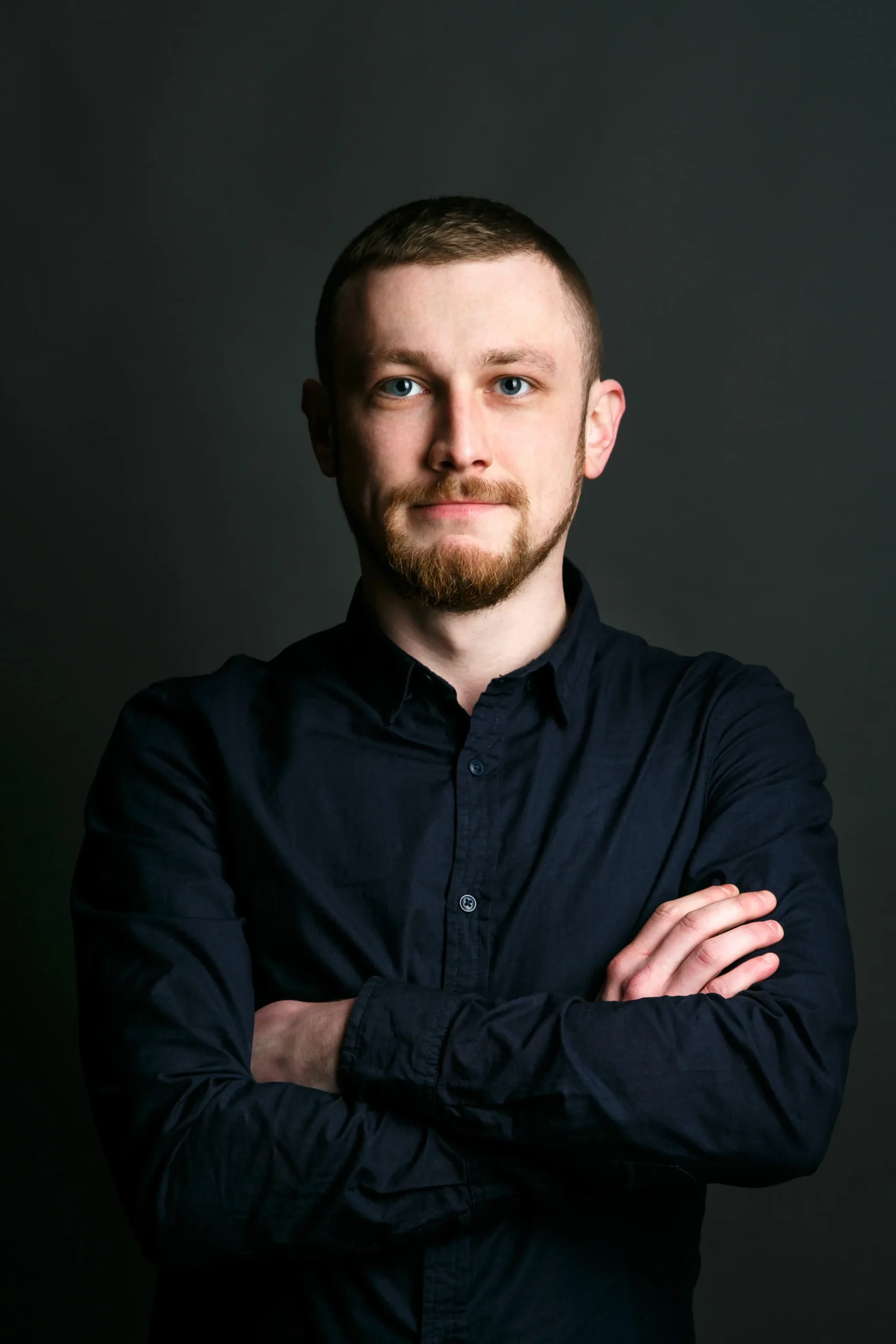 dark-blonde-bearded-man-crosses-his-hands-chest-posing-black-shirt